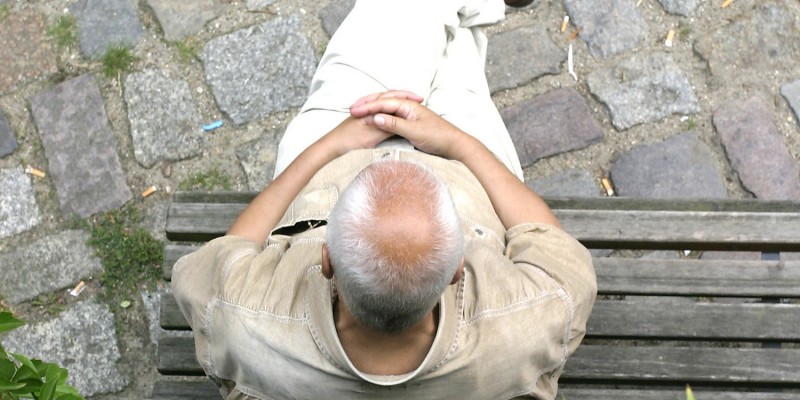 Senior sitzt auf Holzbank