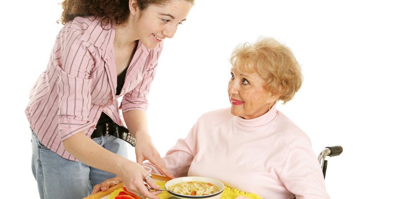 Junge Frau bringt Seniorin das Essen